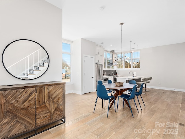 dining space with a healthy amount of sunlight, sink, and light hardwood / wood-style flooring