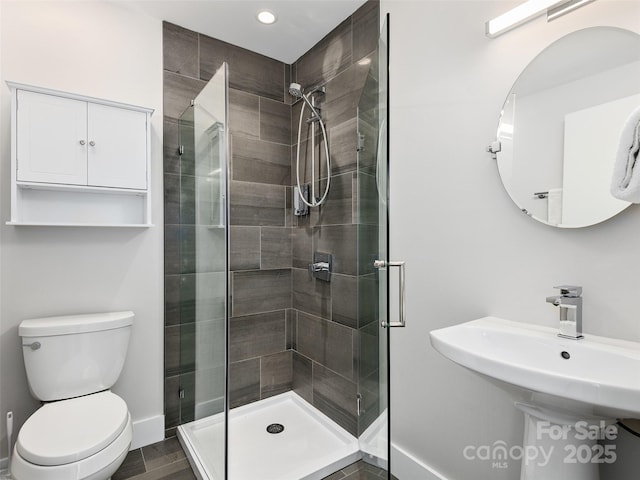 bathroom featuring wood-type flooring, a shower with shower door, sink, and toilet