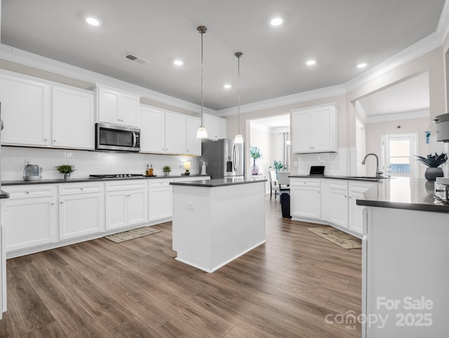 kitchen with pendant lighting, appliances with stainless steel finishes, sink, and white cabinets