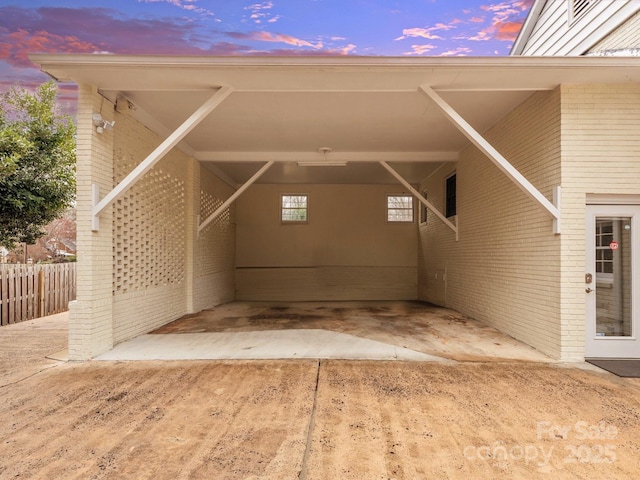 exterior space featuring an attached carport, fence, and brick siding