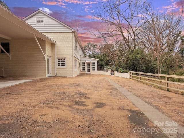 view of property exterior with central AC unit, fence, and brick siding