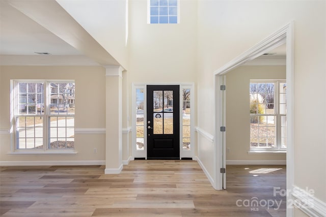 foyer with crown molding, light hardwood / wood-style flooring, and a high ceiling