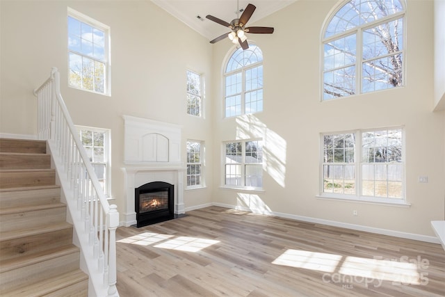 unfurnished living room with ceiling fan, a healthy amount of sunlight, and light wood-type flooring