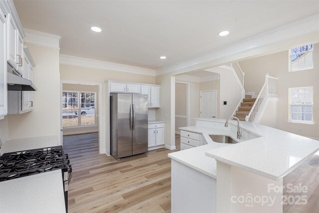 kitchen featuring sink, white cabinetry, ornamental molding, appliances with stainless steel finishes, and a kitchen island with sink