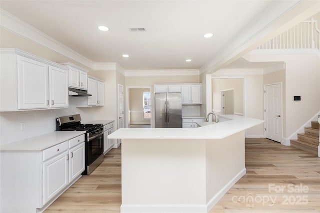 kitchen with a kitchen island with sink, stainless steel appliances, white cabinets, and light wood-type flooring