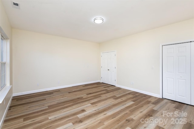 unfurnished bedroom with multiple closets and light hardwood / wood-style floors