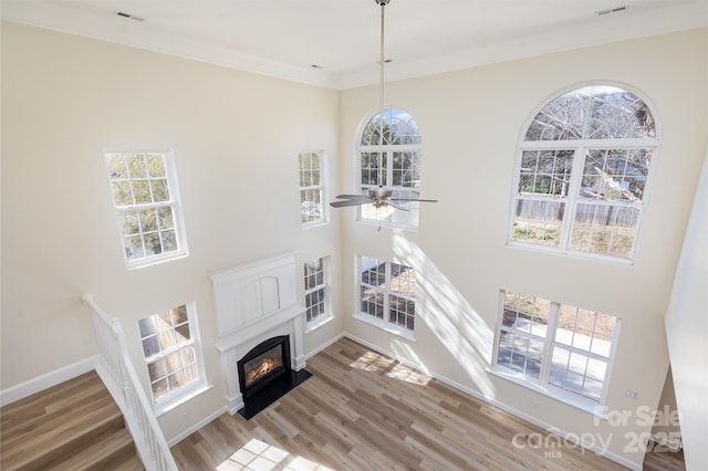 living room with a healthy amount of sunlight, ornamental molding, wood-type flooring, and ceiling fan