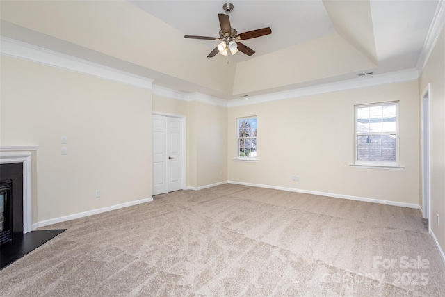 unfurnished living room featuring a healthy amount of sunlight, a tray ceiling, and light carpet