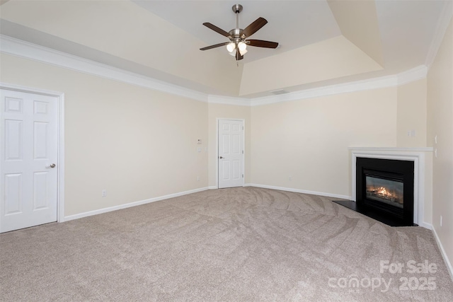 unfurnished living room featuring a raised ceiling, crown molding, carpet flooring, and ceiling fan