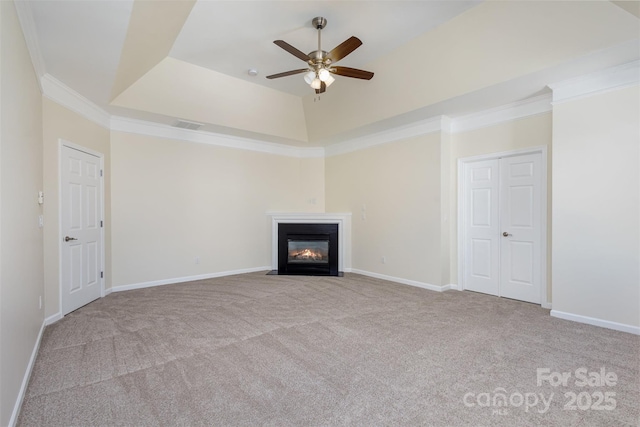 unfurnished living room featuring a raised ceiling, crown molding, light colored carpet, and ceiling fan