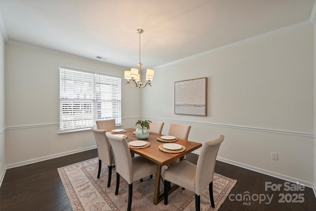 dining space with crown molding, dark hardwood / wood-style flooring, and an inviting chandelier