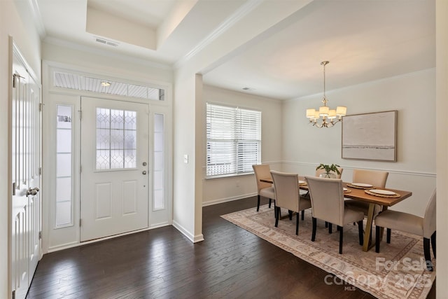 entrance foyer featuring crown molding, a tray ceiling, dark hardwood / wood-style floors, and an inviting chandelier