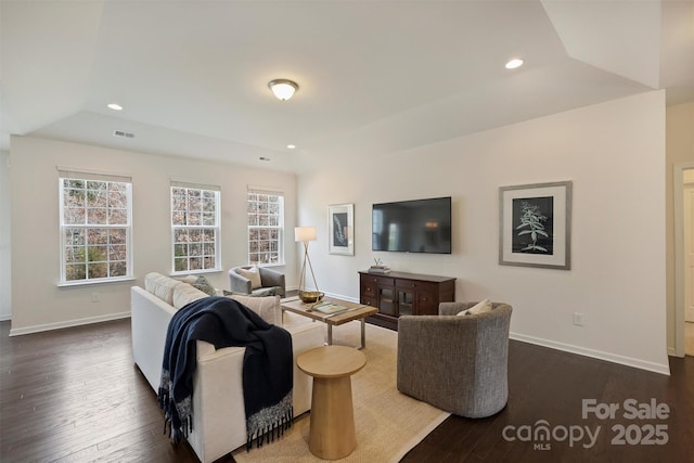 living room with a tray ceiling and dark hardwood / wood-style floors