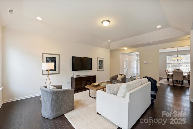 living room with dark wood-type flooring, lofted ceiling, and an inviting chandelier