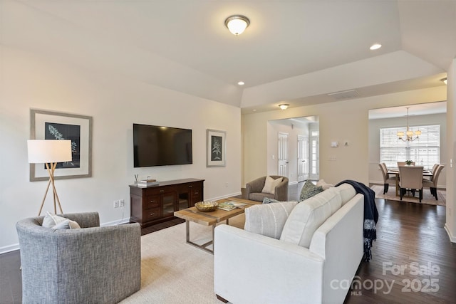 living room with hardwood / wood-style flooring, a raised ceiling, lofted ceiling, and a notable chandelier