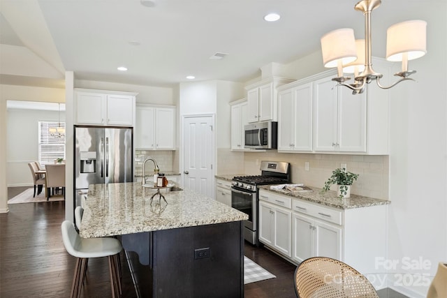 kitchen with sink, white cabinetry, decorative light fixtures, a center island with sink, and appliances with stainless steel finishes