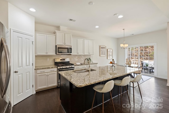 kitchen featuring pendant lighting, white cabinetry, stainless steel appliances, and a kitchen island with sink