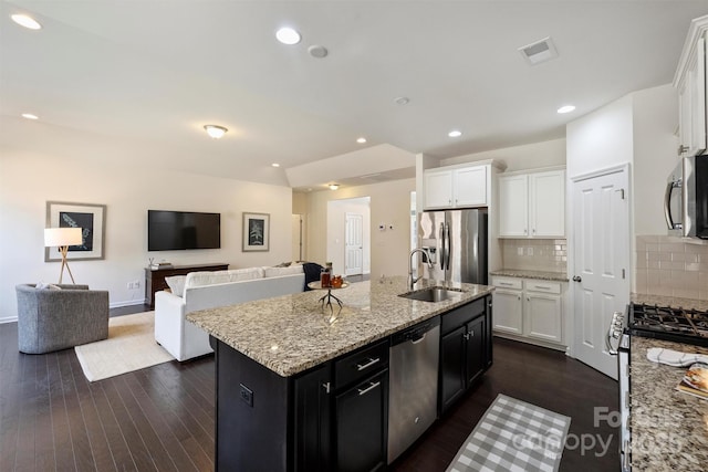 kitchen with white cabinetry, stainless steel appliances, sink, and an island with sink