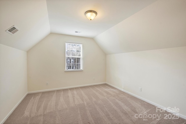 additional living space with light colored carpet and vaulted ceiling