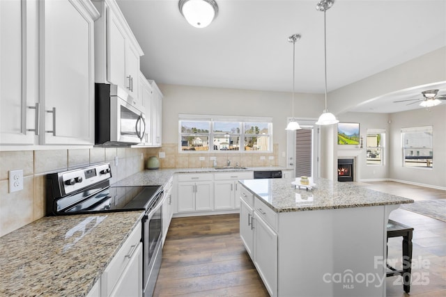 kitchen featuring appliances with stainless steel finishes, a breakfast bar, pendant lighting, white cabinets, and a center island