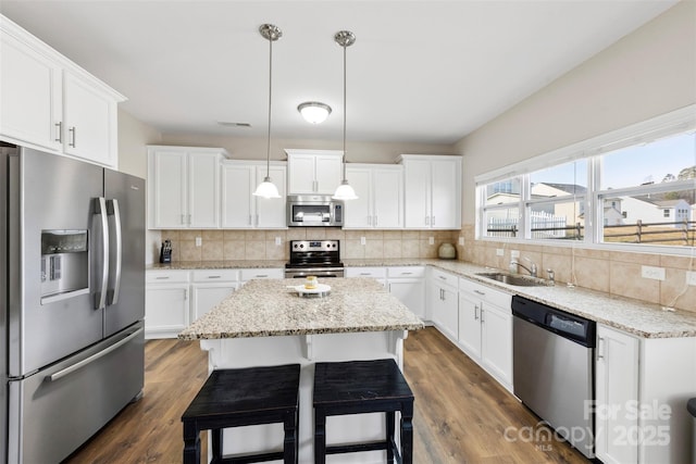 kitchen featuring pendant lighting, white cabinetry, a breakfast bar area, a center island, and stainless steel appliances