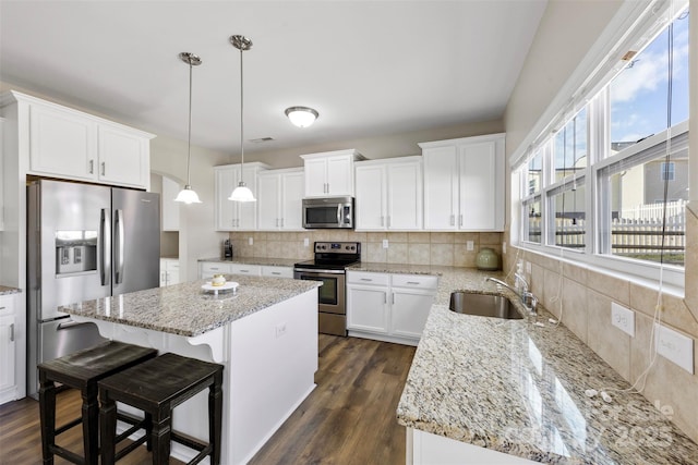 kitchen with pendant lighting, sink, white cabinets, a center island, and stainless steel appliances