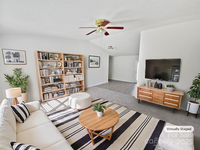 living room with a textured ceiling, vaulted ceiling, ceiling fan, and dark colored carpet