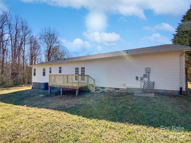 rear view of property featuring a wooden deck and a lawn