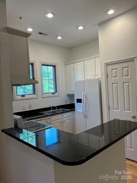 kitchen featuring white cabinetry, sink, white fridge with ice dispenser, light hardwood / wood-style floors, and kitchen peninsula