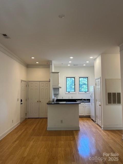 kitchen with white fridge, white cabinets, and light wood-type flooring