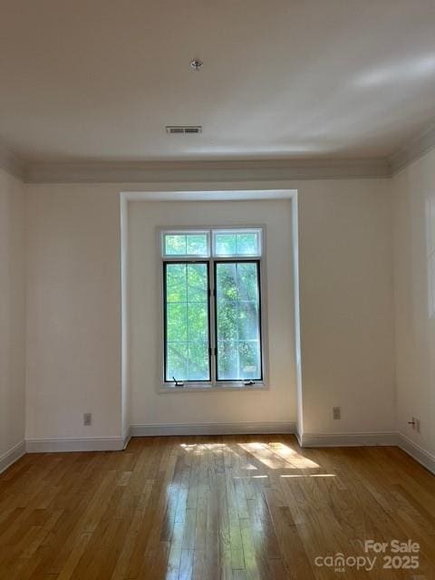 empty room featuring ornamental molding and light hardwood / wood-style floors