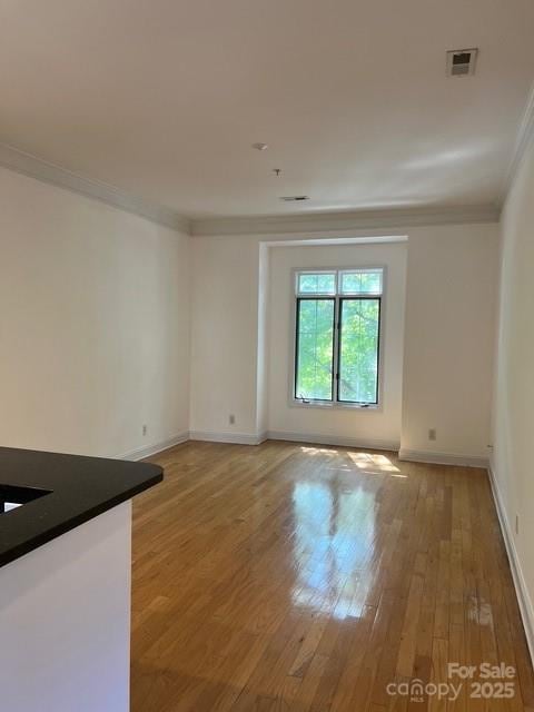 empty room with ornamental molding and hardwood / wood-style floors