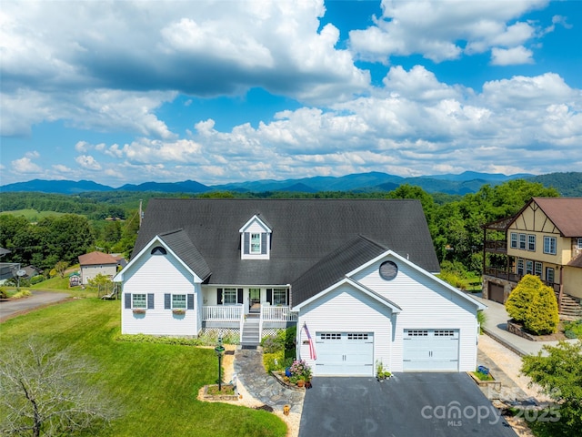 view of front of home featuring a garage, a mountain view, covered porch, and a front lawn