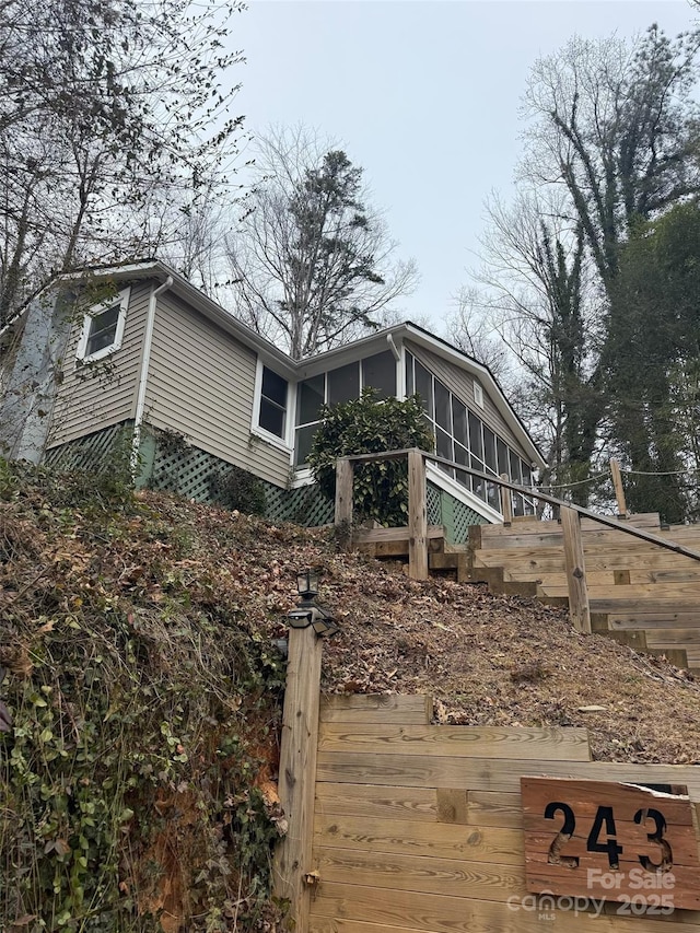 view of home's exterior with a wall unit AC and a sunroom