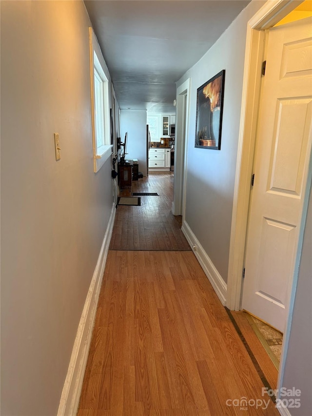 corridor featuring baseboards and wood finished floors