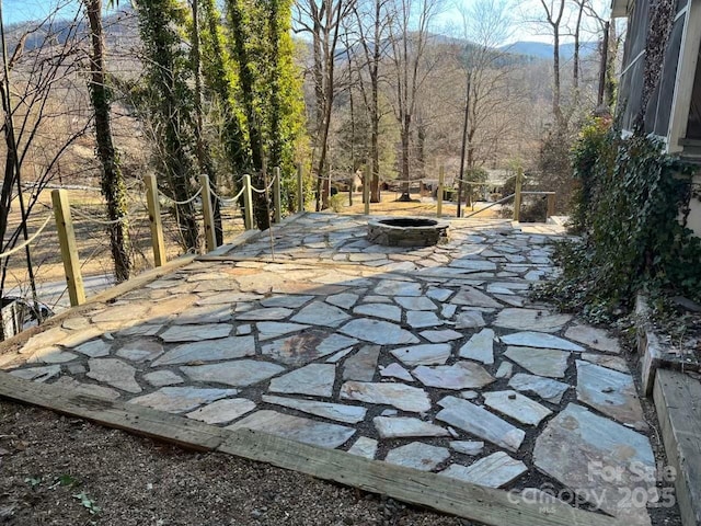 view of patio with an outdoor fire pit and a view of trees