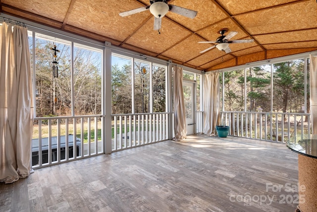 unfurnished sunroom featuring ceiling fan, a healthy amount of sunlight, and vaulted ceiling