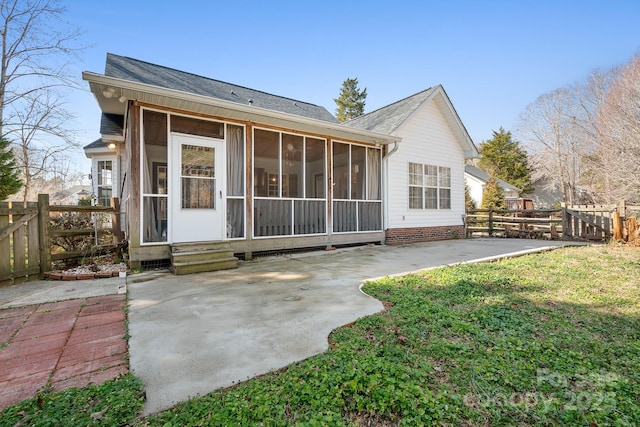 rear view of house with a yard, a patio area, and a sunroom