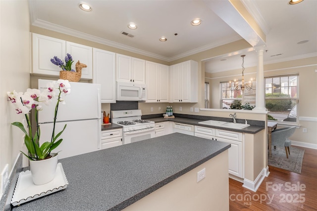 kitchen featuring decorative columns, sink, white appliances, and kitchen peninsula