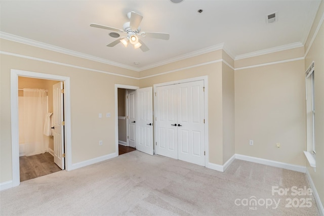 unfurnished bedroom featuring ceiling fan, light colored carpet, ornamental molding, and connected bathroom