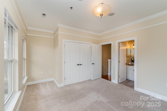 unfurnished bedroom featuring crown molding, carpet flooring, ensuite bathroom, and a closet