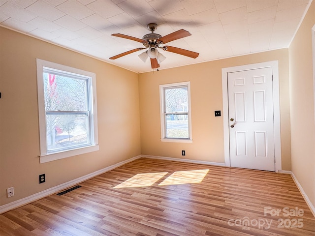 spare room with plenty of natural light, ceiling fan, and light wood-type flooring