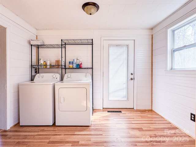 laundry area with independent washer and dryer and light hardwood / wood-style flooring