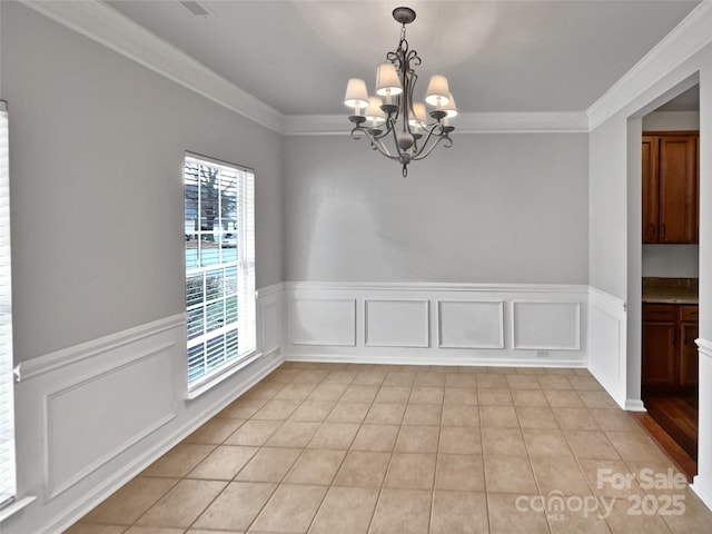 tiled spare room featuring crown molding and a chandelier