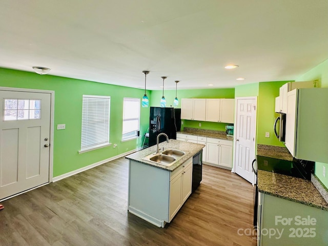 kitchen featuring sink, white cabinetry, an island with sink, pendant lighting, and black appliances