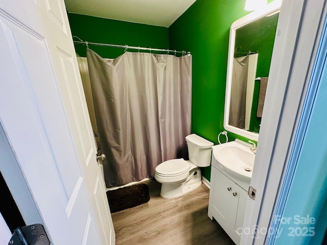 bathroom with wood-type flooring, walk in shower, vanity, and toilet