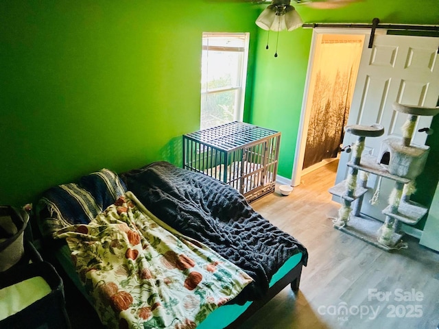 bedroom featuring a barn door and light hardwood / wood-style floors