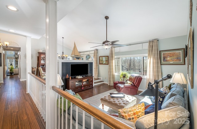 living room featuring dark wood-style floors, decorative columns, vaulted ceiling, and ceiling fan with notable chandelier