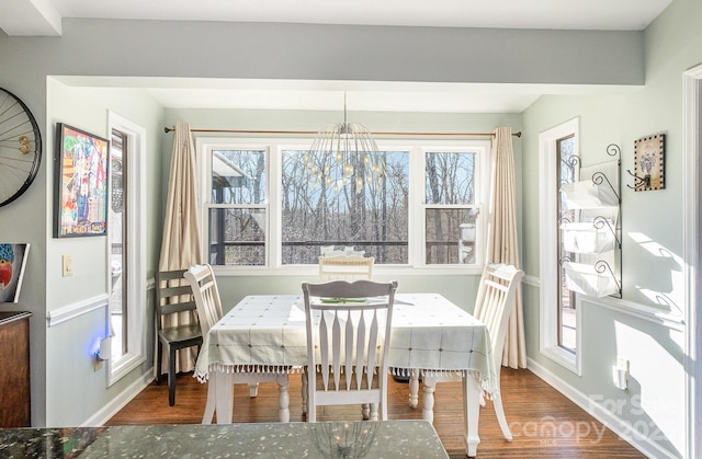 dining area with a chandelier, baseboards, and wood finished floors