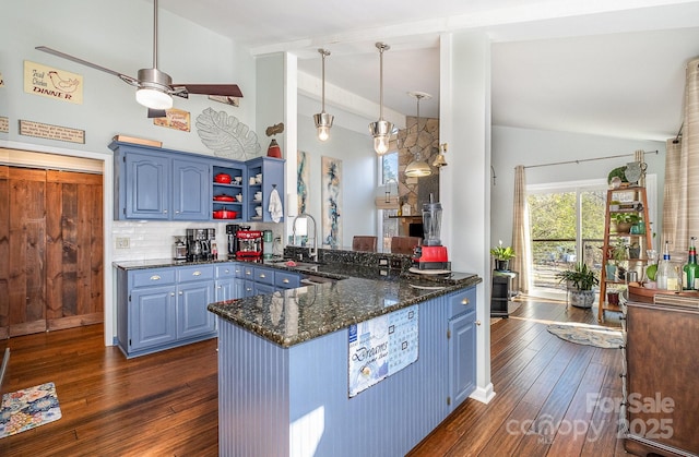 kitchen featuring dark wood-type flooring, dark stone countertops, a peninsula, blue cabinetry, and open shelves